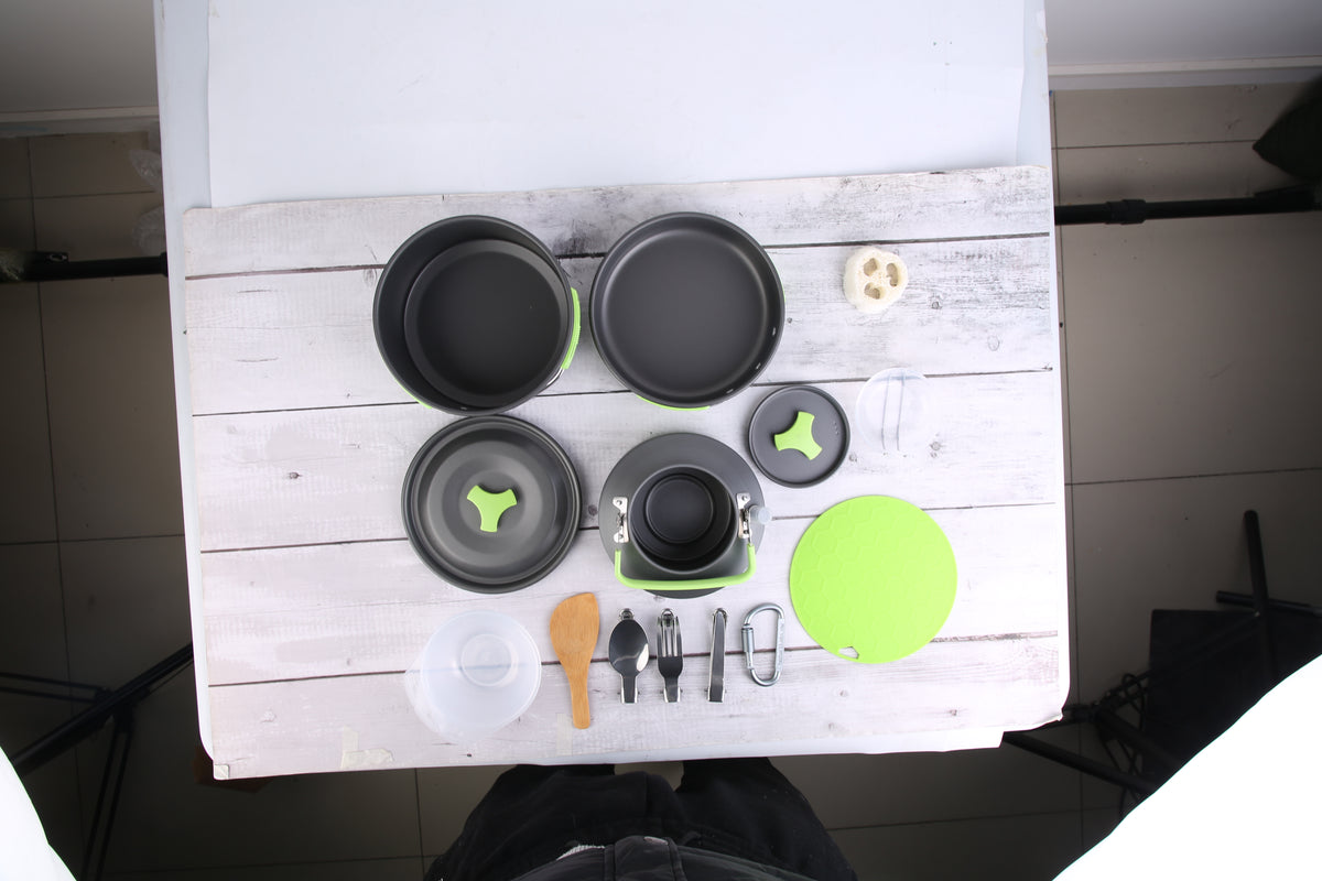 Set of black cookware and utensils on a white wooden surface