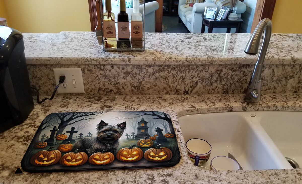 Halloween-themed mat with a raccoon and pumpkins on a kitchen counter.